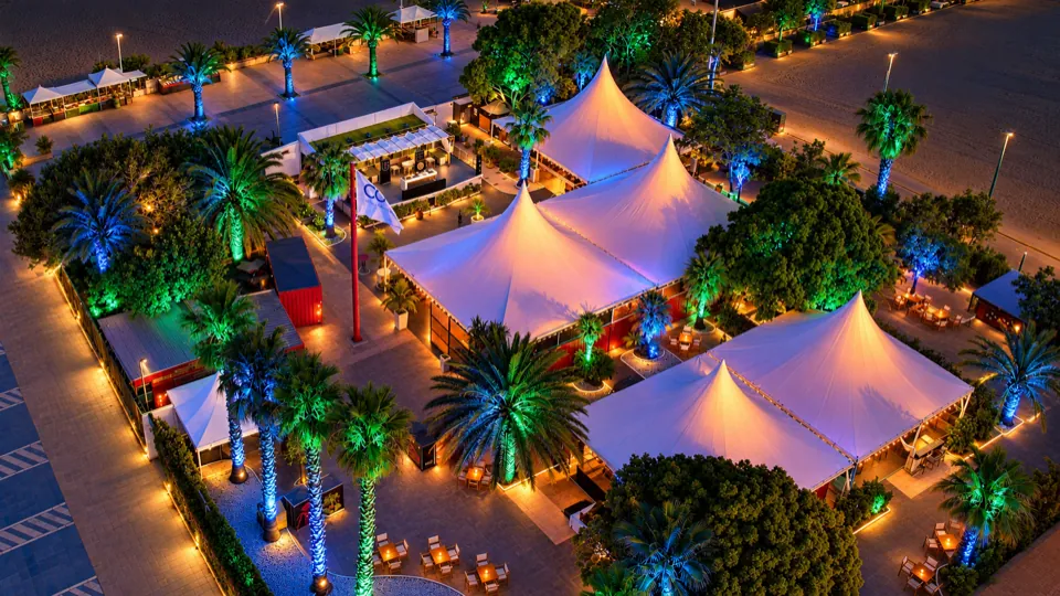 Cocoa Beach Club from the air at night, with the marquees and palm trees lit up